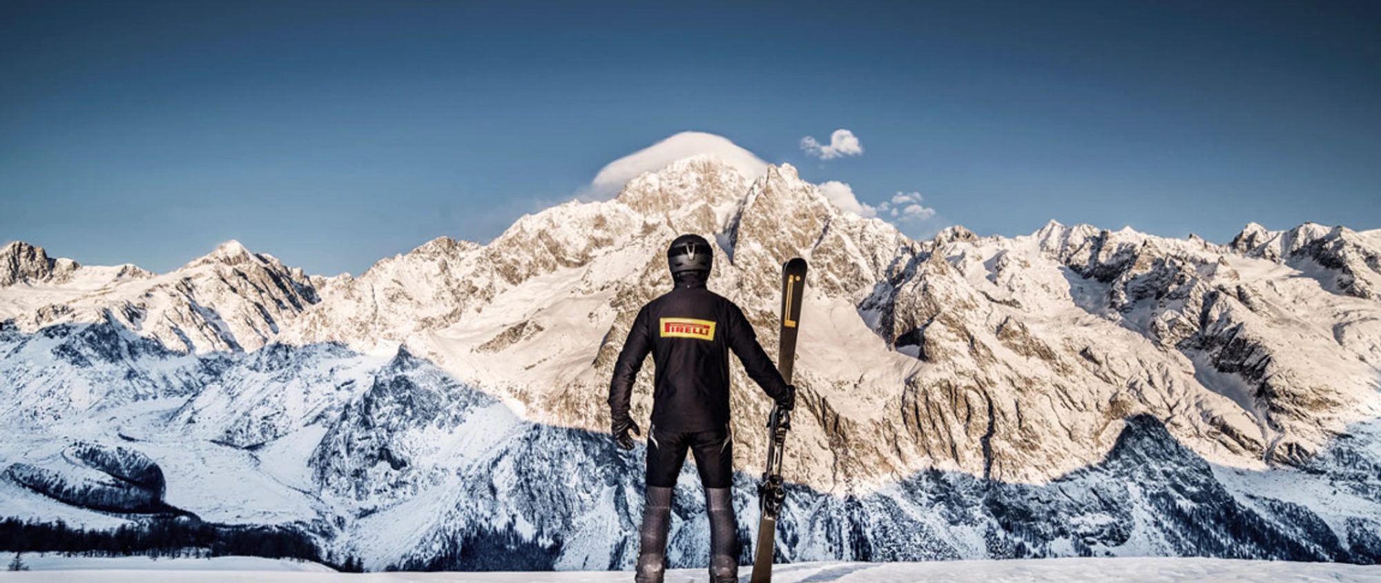 Skifahrer mit PIRELLI vor Bergpanorama
